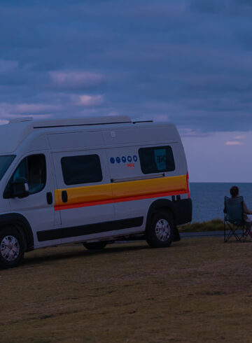 Fernanda sitting on a chair in front of a motorhome watching the full moon on the horizon in Australia