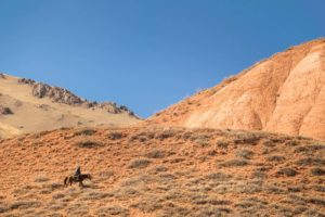 Homem cavalgando sozinho nas montanhas do Quirguistão