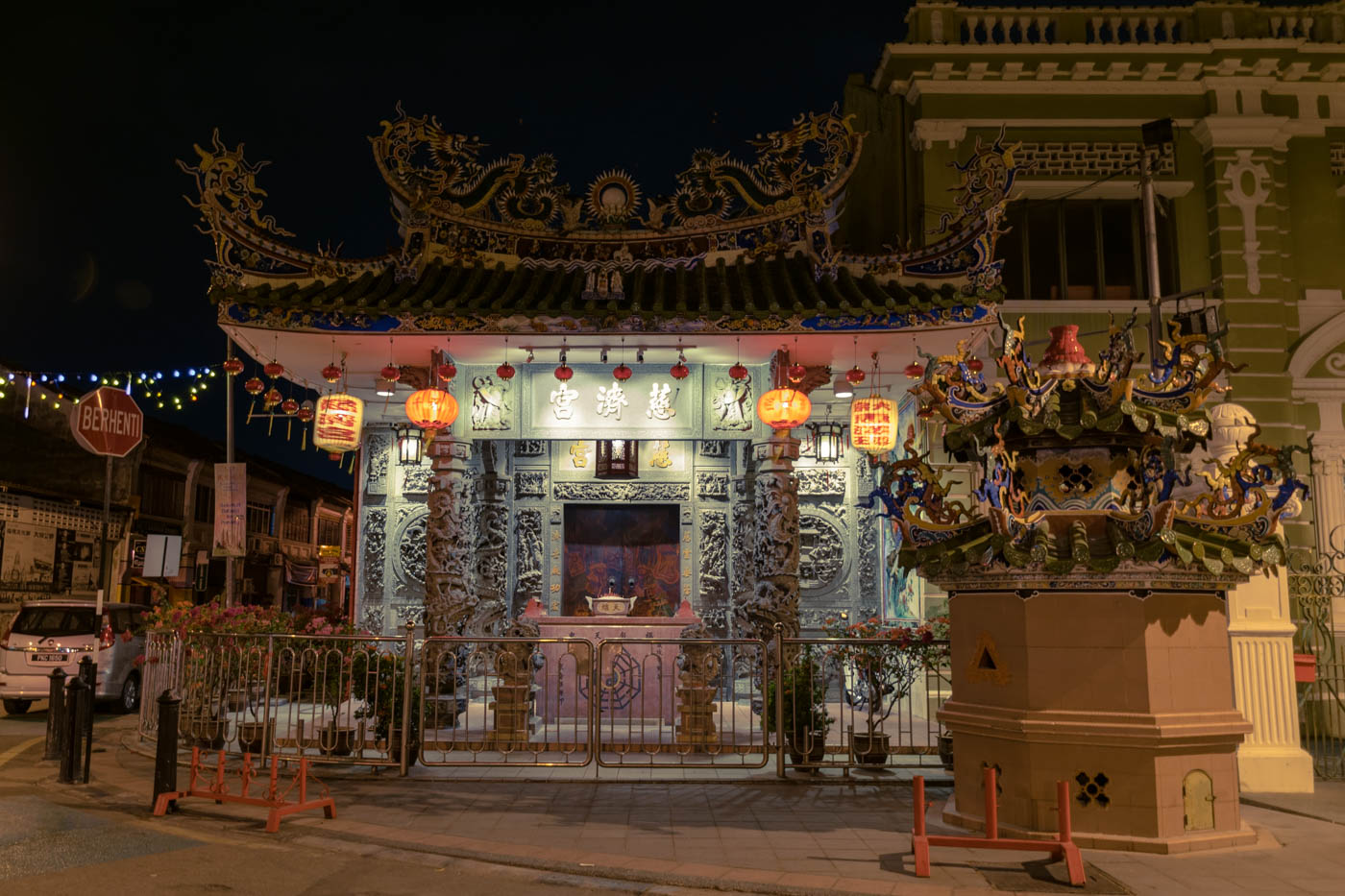 Um templo em uma esquina das ruas de Penang a noite, bem iluminado e decorado