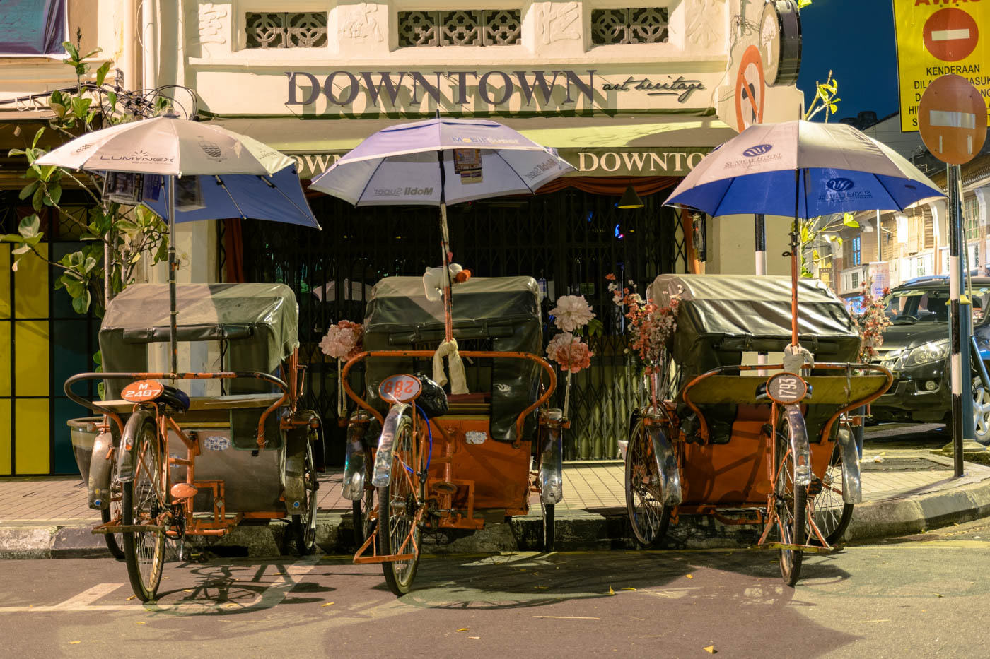 Três tuktuks de bicicleta estacionados na rua a noite em Penang