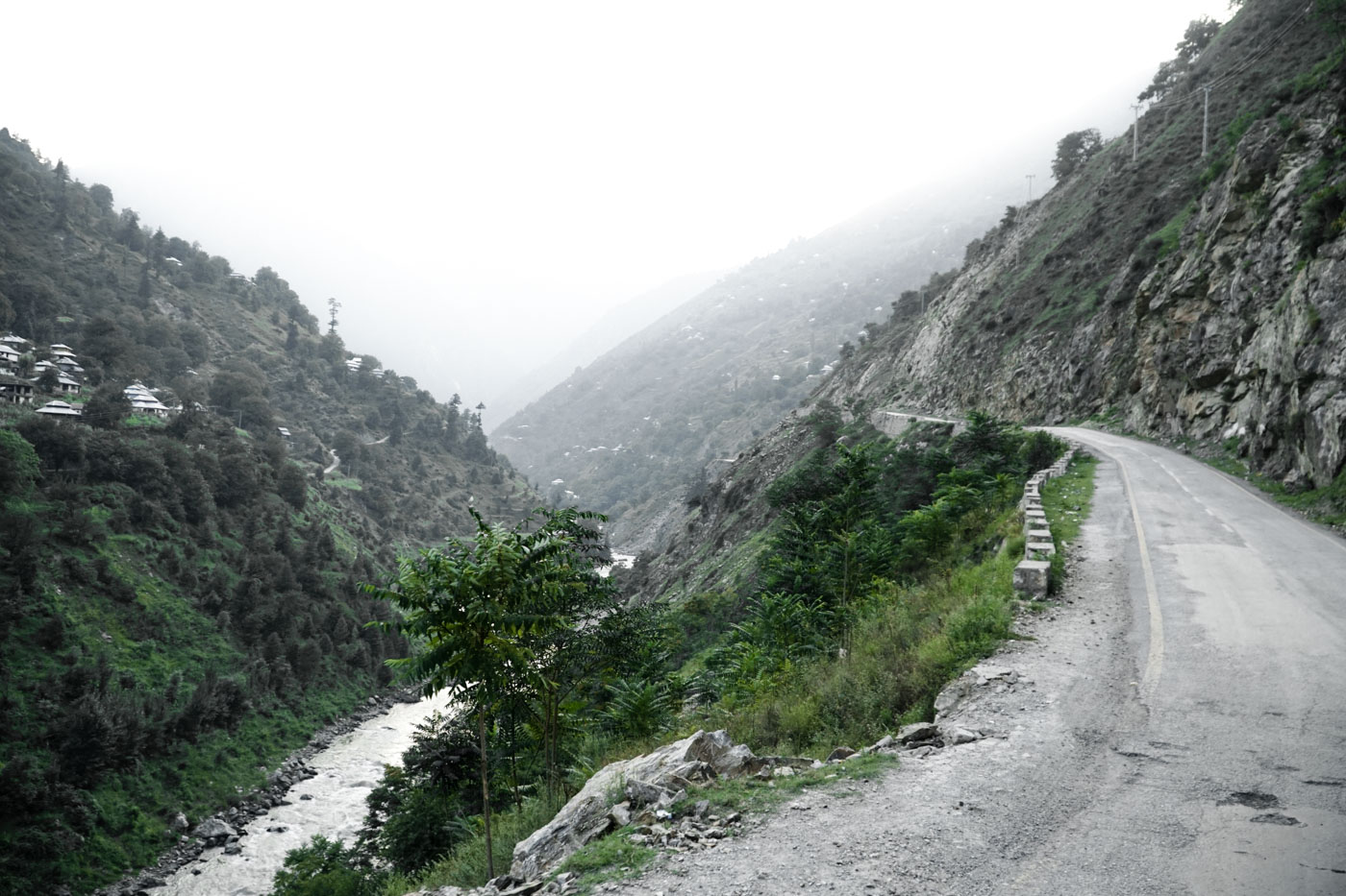 A bad road to Hunza Valley with a stream of river down the road in a valley