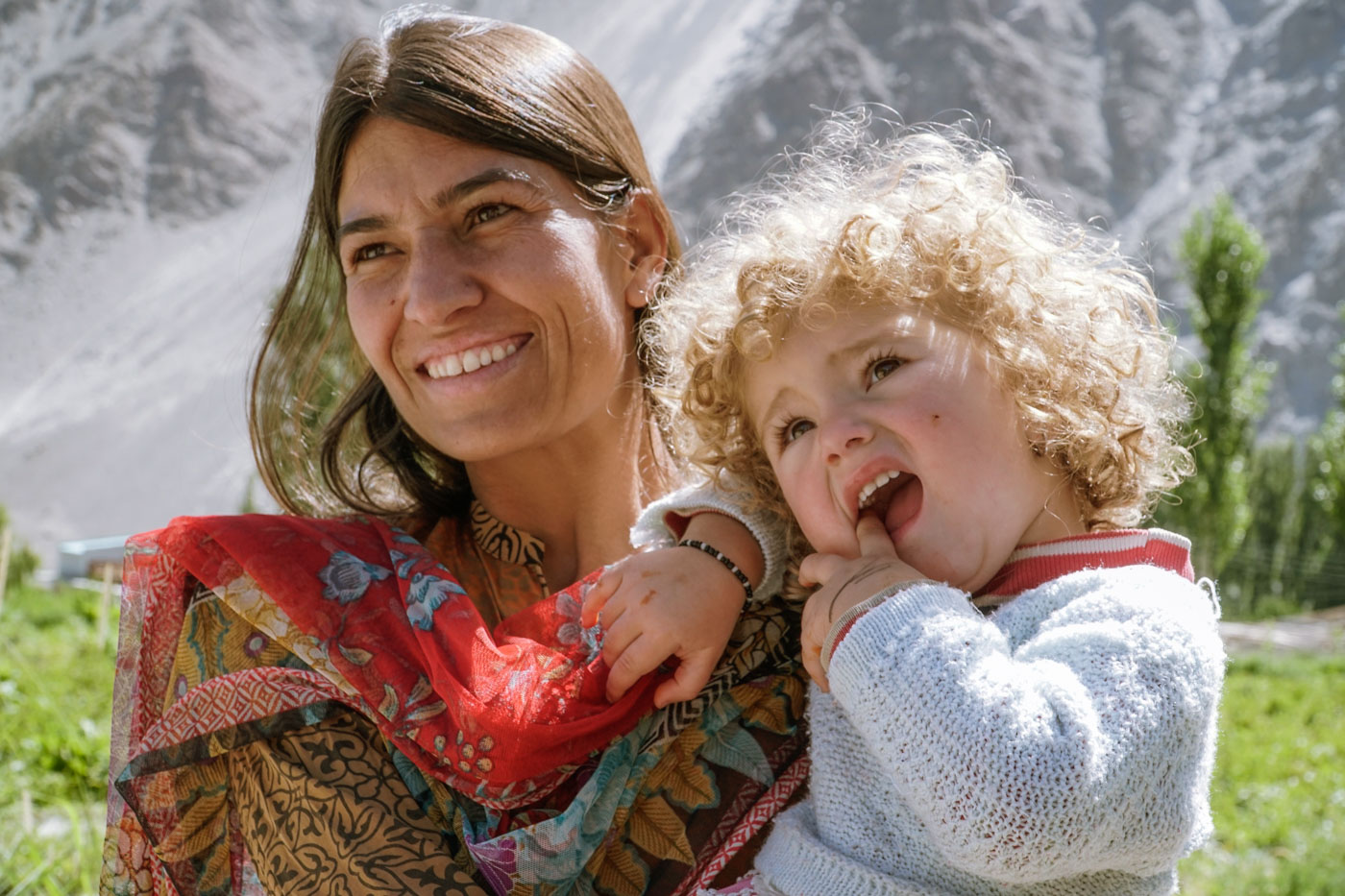 Uma mãe segurando sua filha no colo com roupas coloridas típicas do vale de hunza