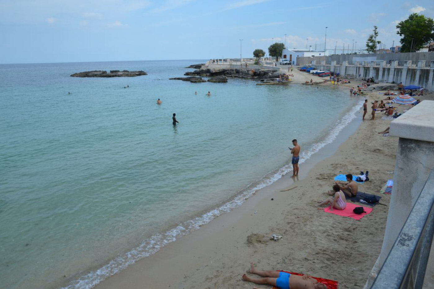 Praia com pouca areia em Monopoli na Puglia e algumas pessoas tomando sol
