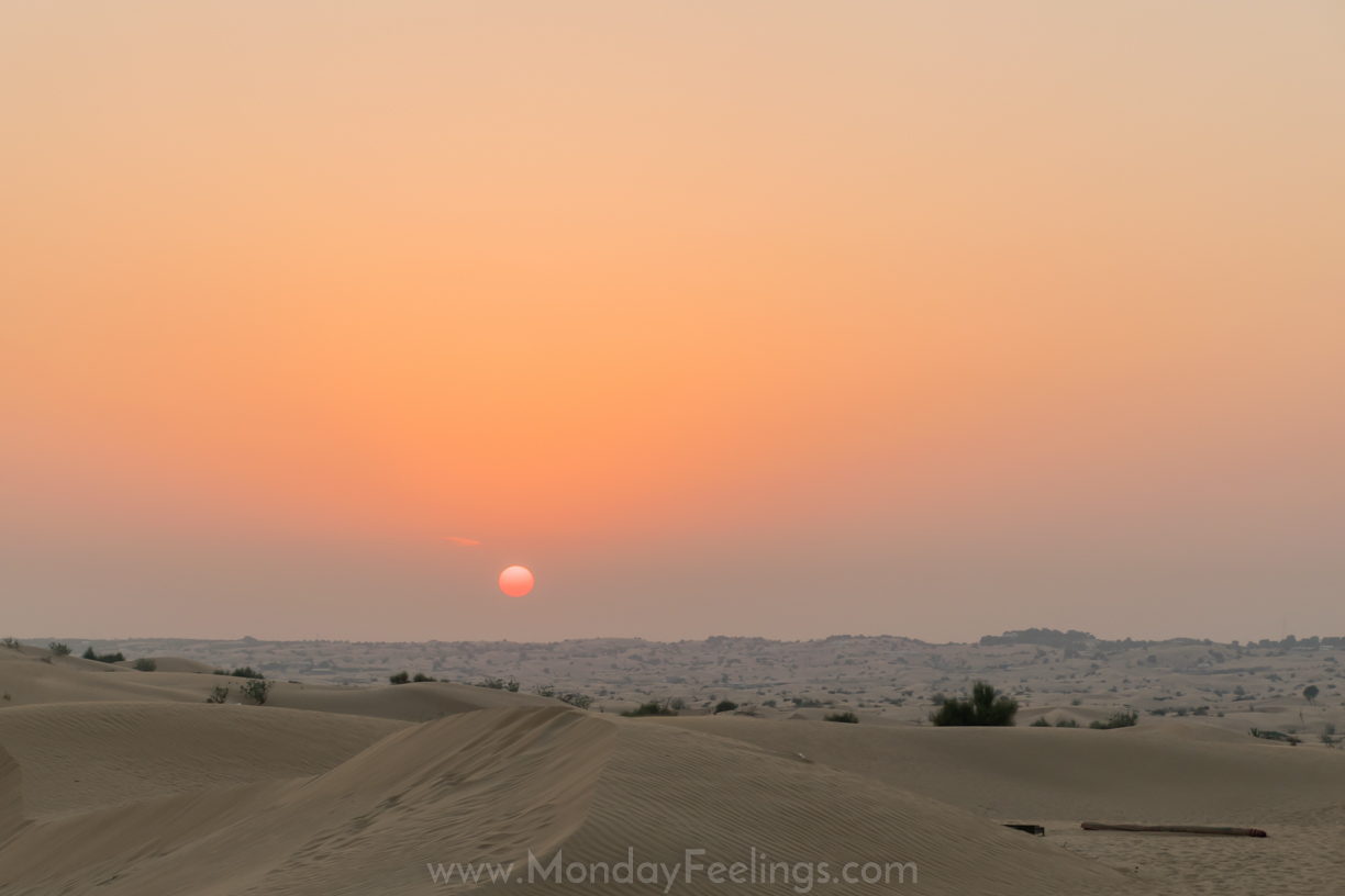 A sun setting in the horizon of Dubai from its desert