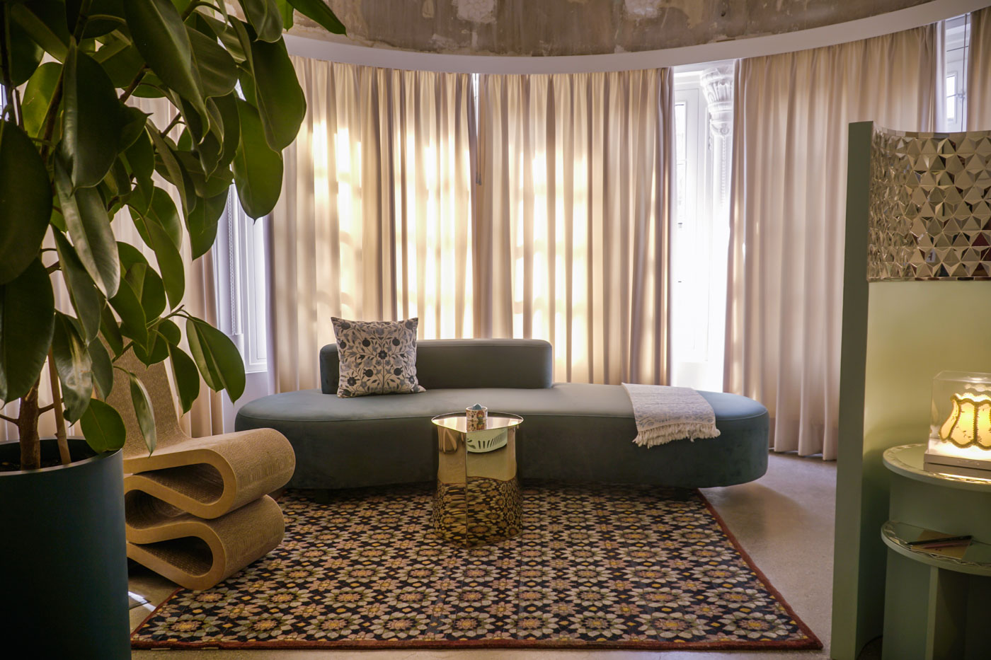the room of Hanna Boutique Hotel showing a sofa and a modern seat in the room with closed curtains and a tall vase