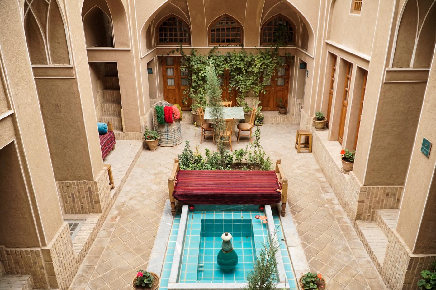 Salão de hotel tradicional do Irã com uma fonte no meio muitas janelas em volta
