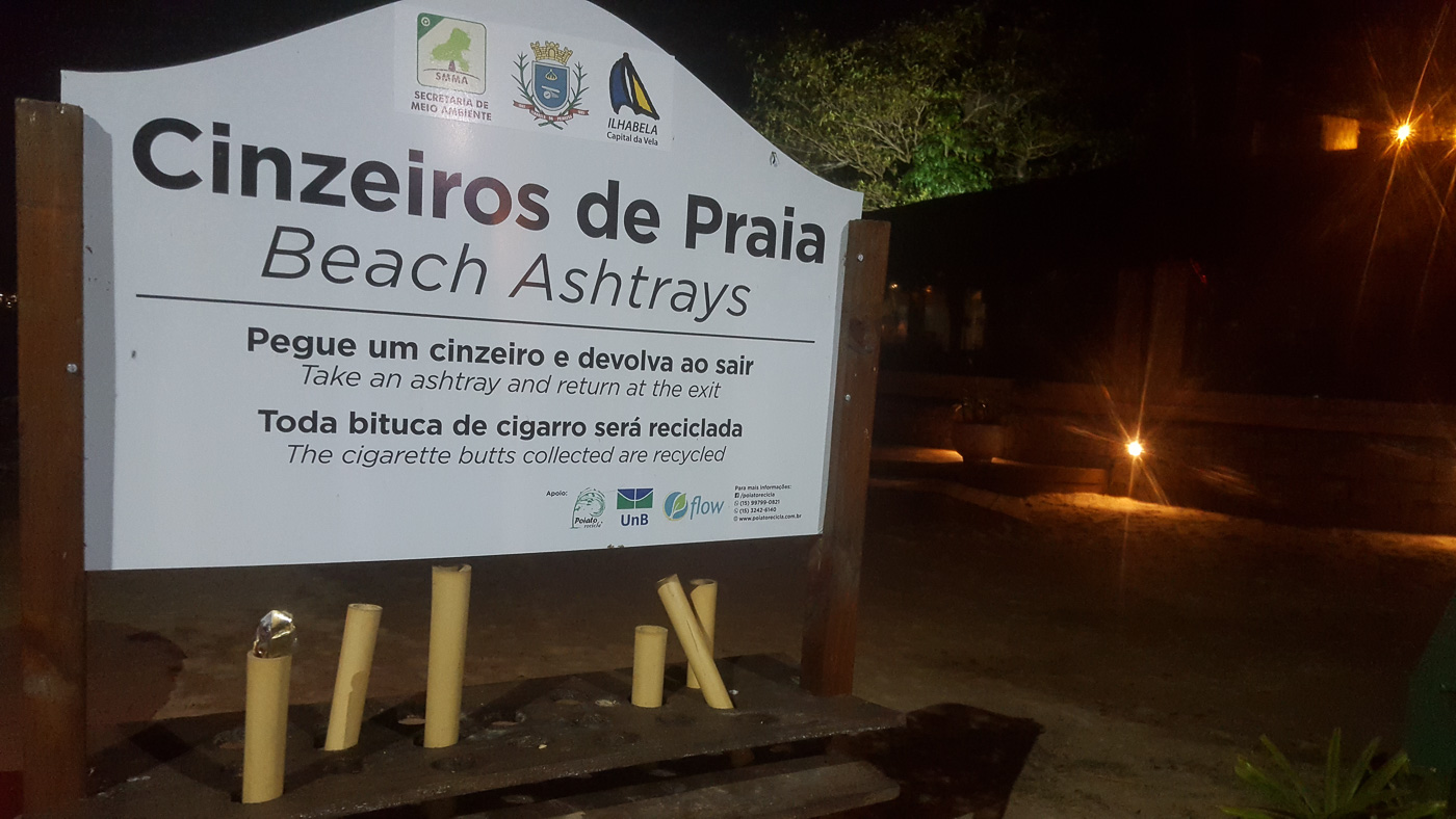 Uma placa a noite na praia falando sobre os cinzeiros de praia