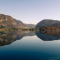 A large lake with a mountain in the background reflected in Bohinj visited when we were cycling in Slovenia