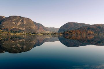 A large lake with a mountain in the background reflected in Bohinj visited when we were cycling in Slovenia