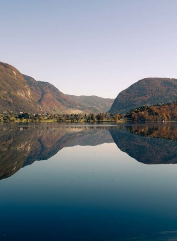 A large lake with a mountain in the background reflected in Bohinj visited when we were cycling in Slovenia