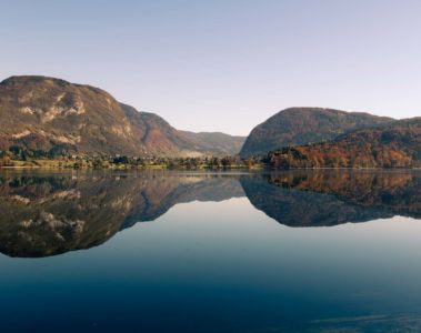 A large lake with a mountain in the background reflected in Bohinj visited when we were cycling in Slovenia