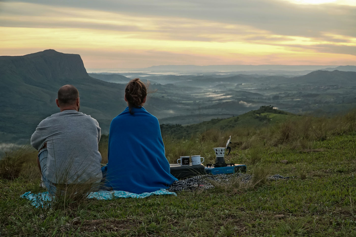 Tiago e Fernanda sentados olhando para o horizonte durante o sol nascendo na Serra da Canastra