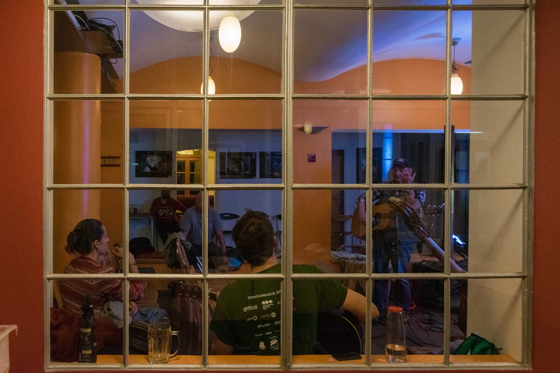 A view through the window of Celica hostel with people enjoy a music gig inside