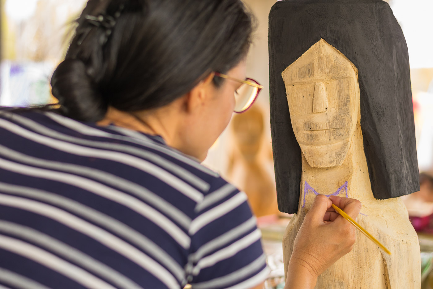 artesã pintando uma escultura de madeira