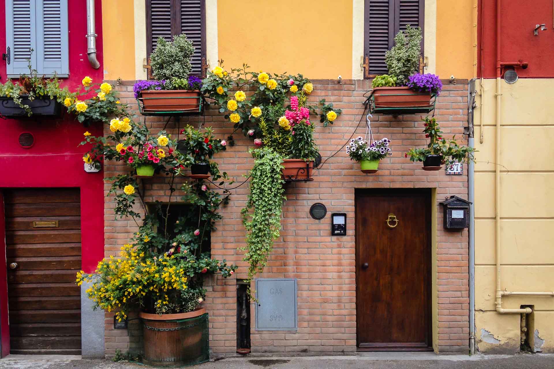 A frente de uma das casas do centro de Parma bem colorida e cheia de flores penduradas