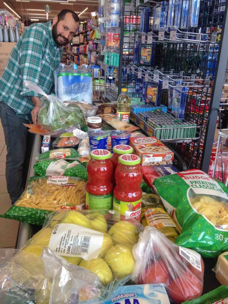 Tiago in the supermarket doing food shopping in Italy with the cashier full of food