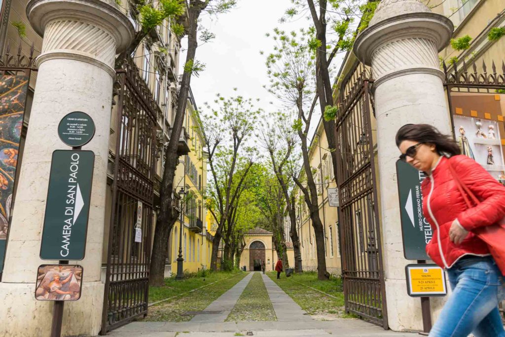 Woman walking past the entrance of a museum in Parma