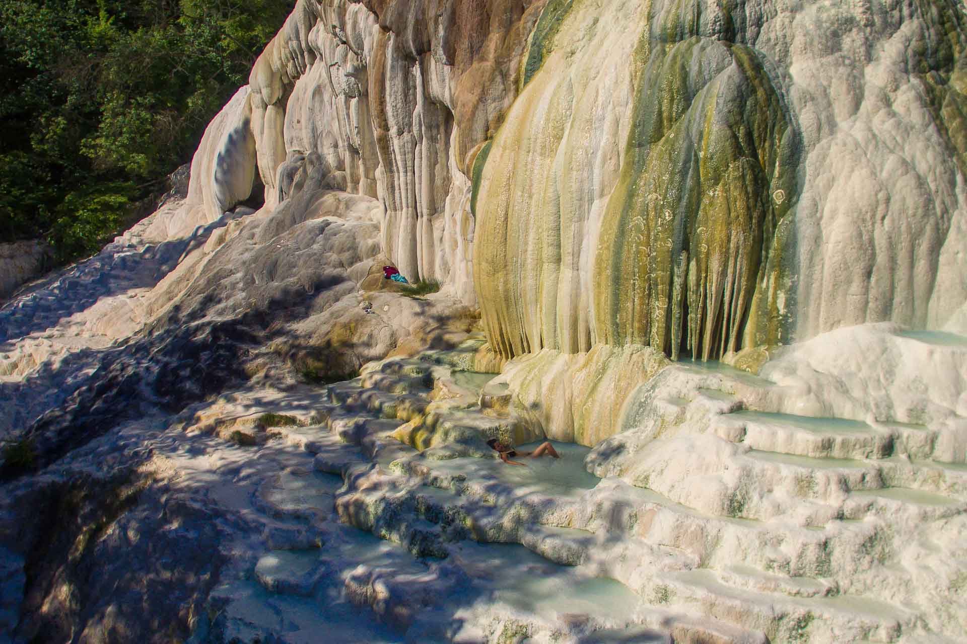 Uma pedra branca grande com alguns buracos de água verde onde a Fernanda está nadando