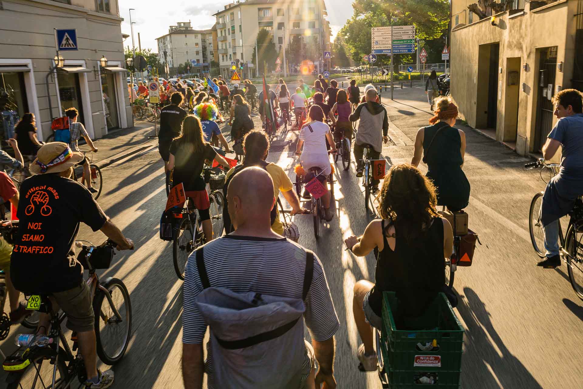 A crowd of people on bikes against the light of the sun in the streets of Florence