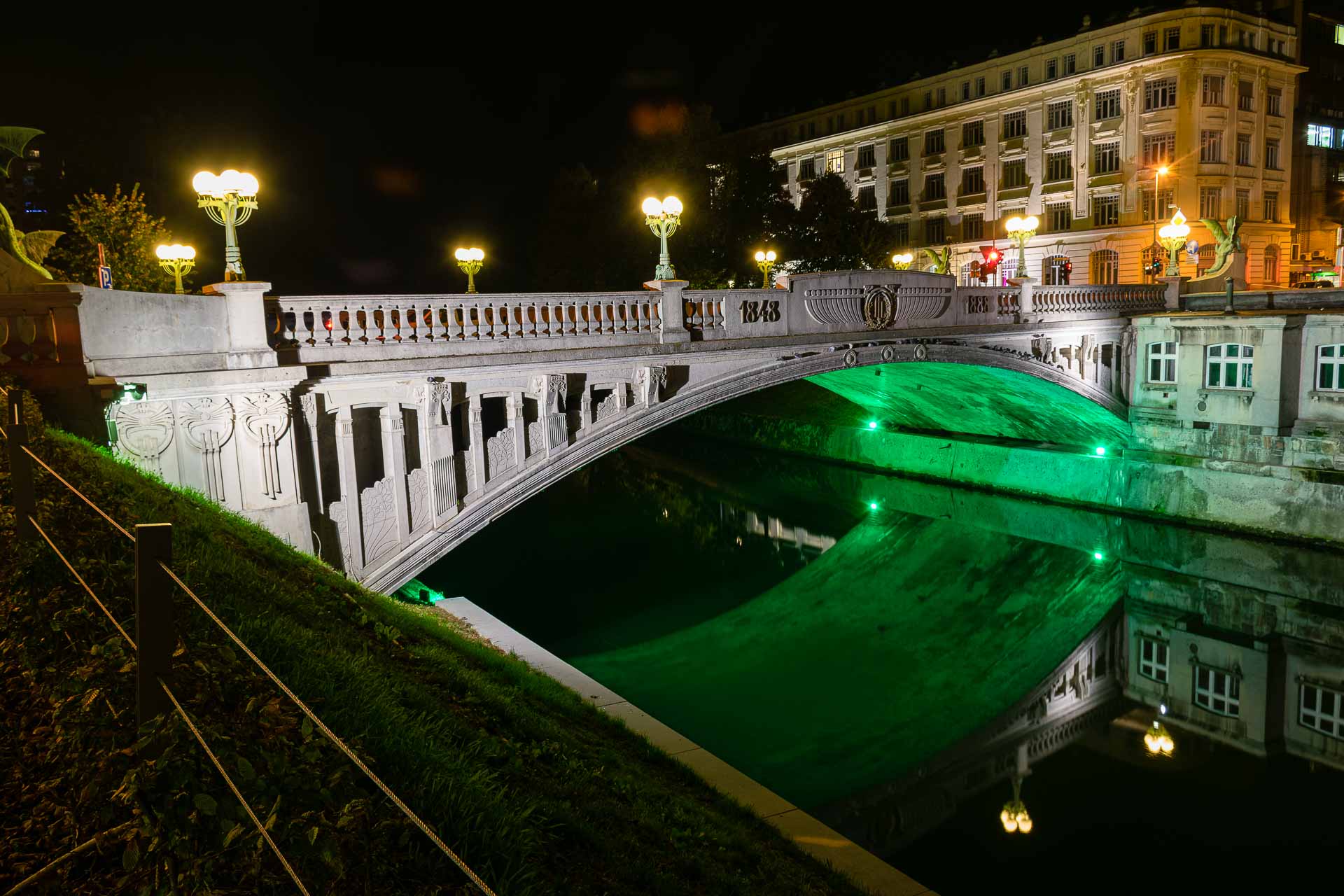 A bridge in Ljubljana at night with green light underneath