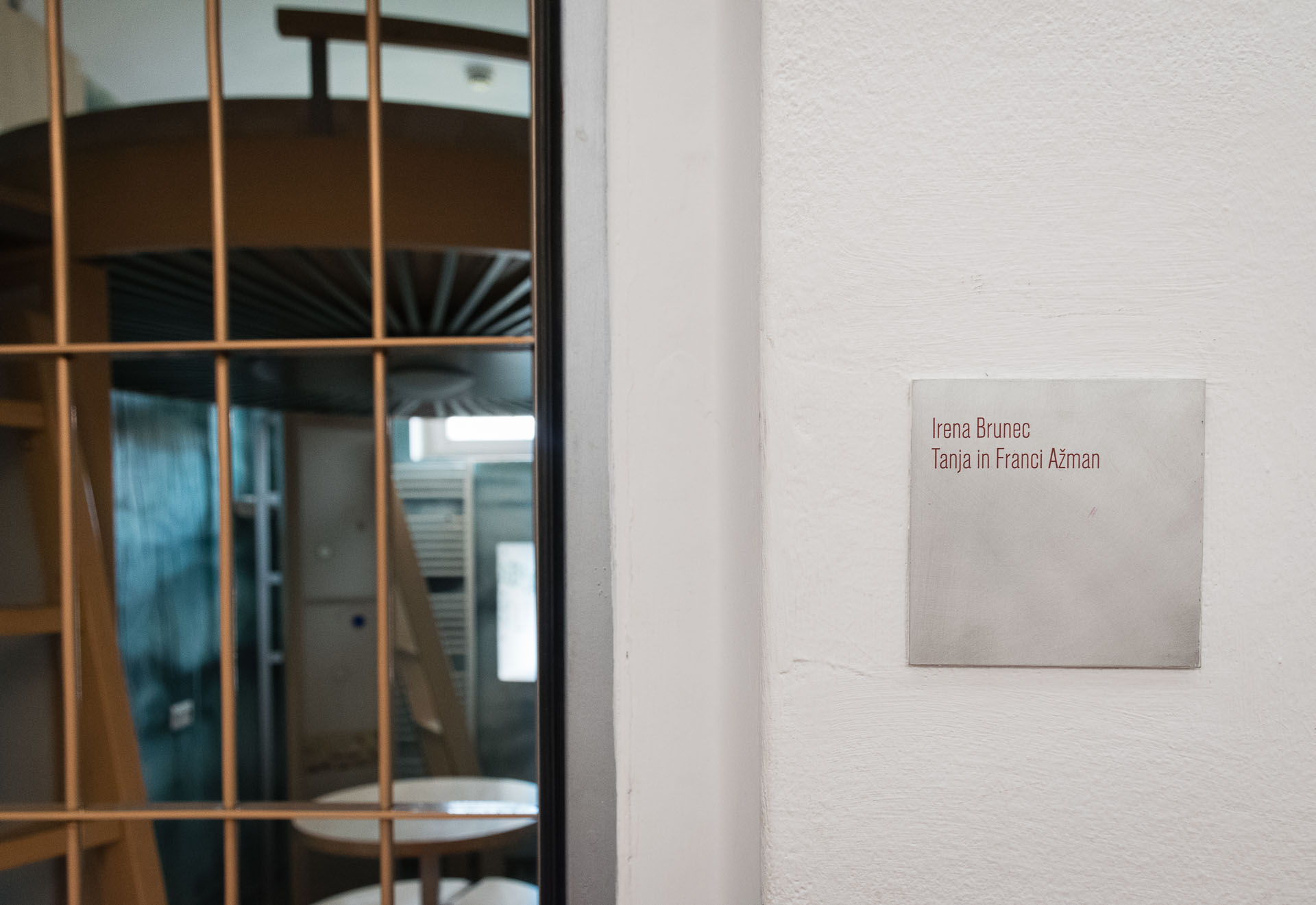 The entrance of the room that looks like the entrance of a prison cell with the name of the artist on the wall