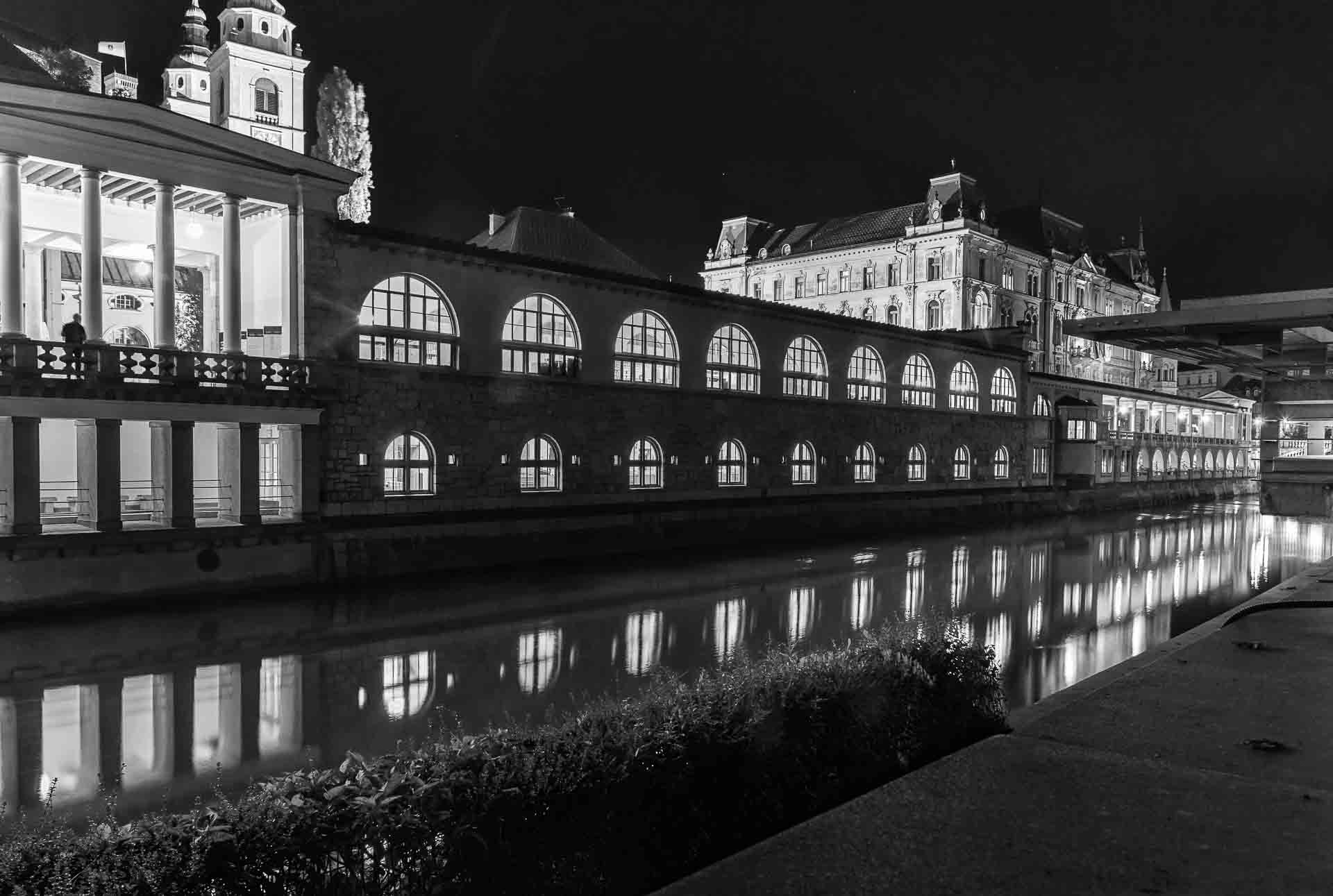 Fotografia em preto e branco da noite de Liubliana com o rio passando na cidade