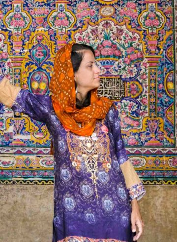 Fe with colourful clothes in front of a mosque with colourful tiles