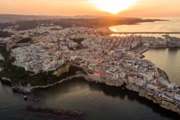 Vista aerea de Vieste no sul da Italia envolta pelo mar com o sol se pondo