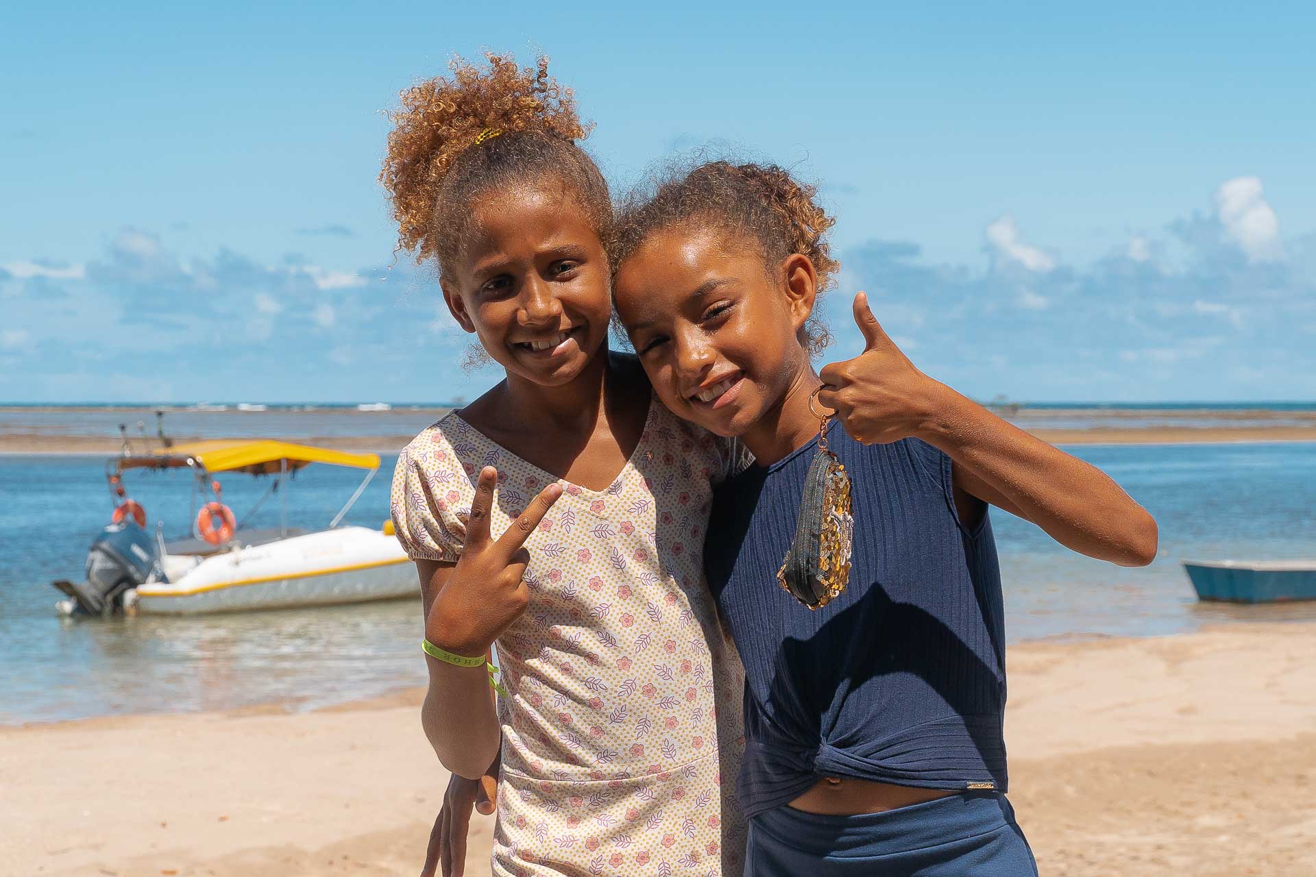 two little girls posing with thumbs up in the beach of Boipeba