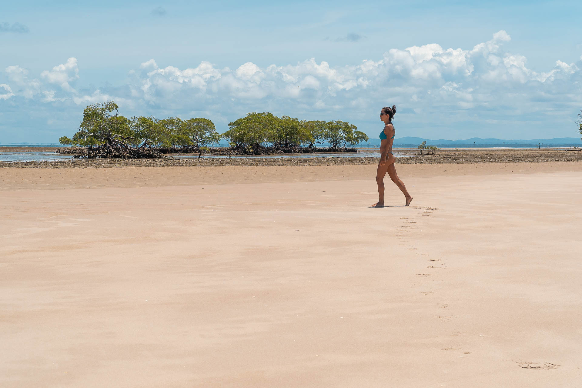 Fernanda walking on the white sandy beach with a lot of space and nothing around