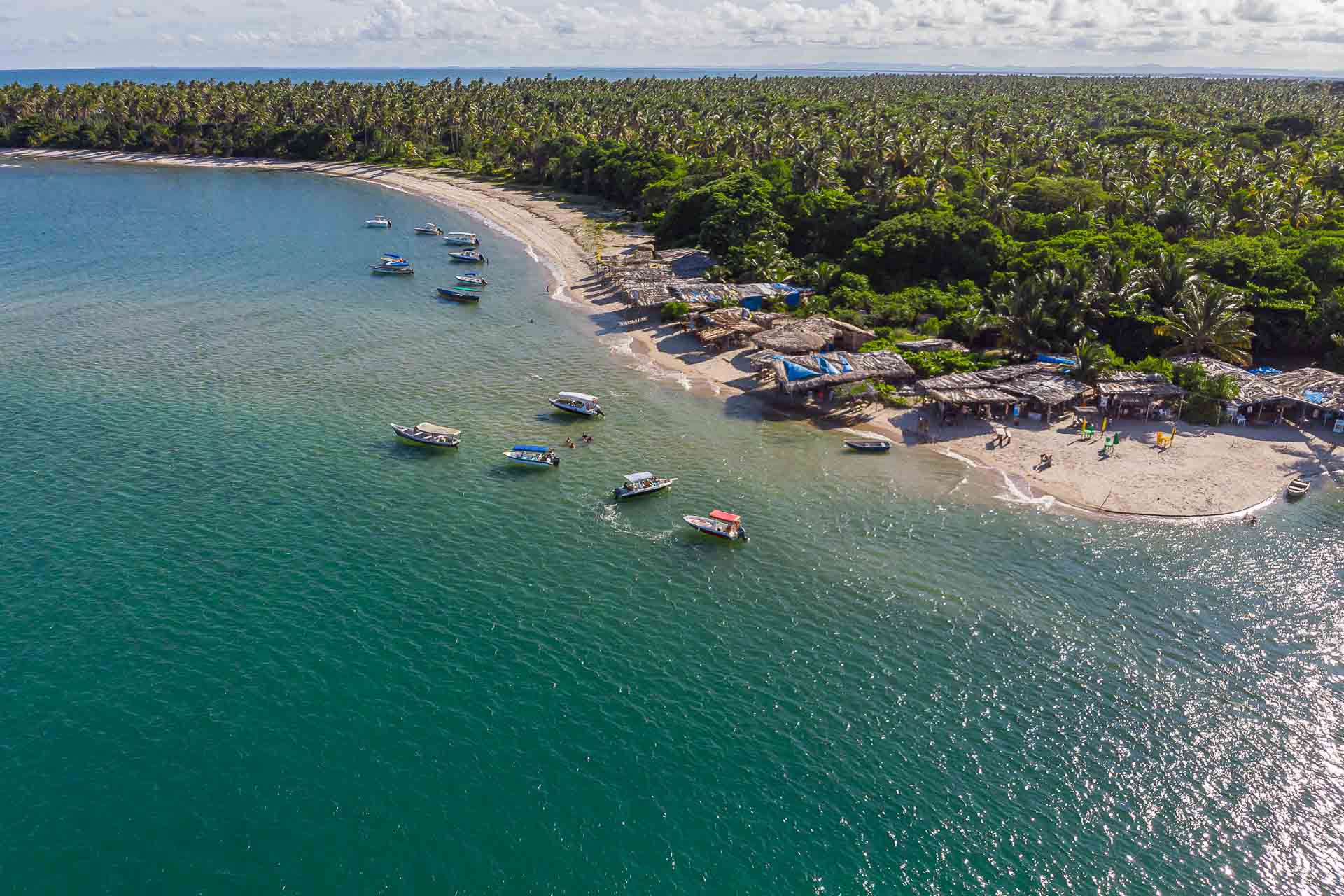 Vista aerea da ponta de Castellanos com algumas barraacs na ponta e uns barcos no mar