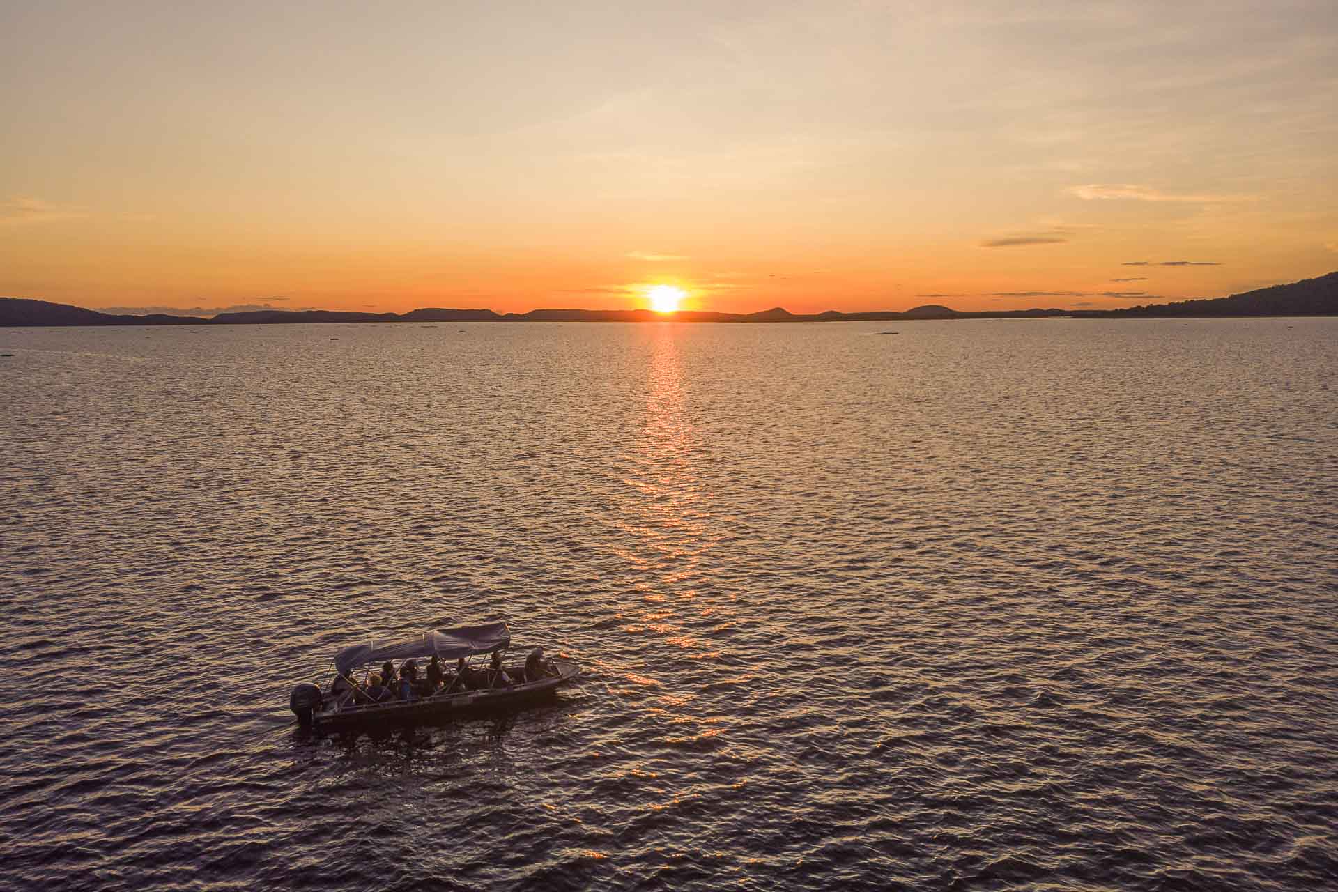 Aerial view of a large lake with a boat watching the sunset