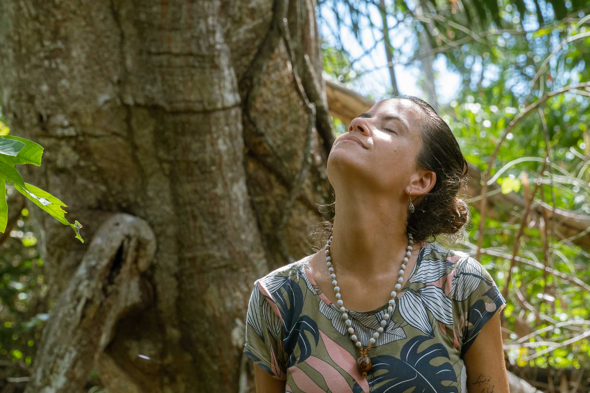 Fernanda sentindo o vento e o sol no rosto na frente de uma arvore na Serra do Amolar