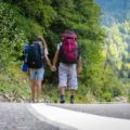 Tiago and Fernanda walking in a road with their backpacks