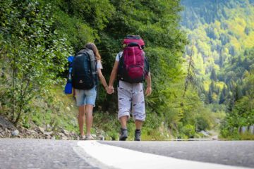 Tiago and Fernanda walking in a road with their backpacks