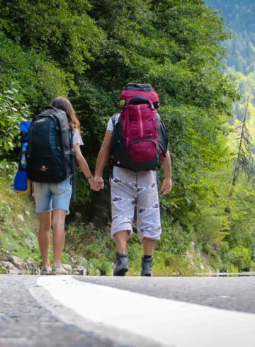 Tiago and Fernanda walking in a road with their backpacks
