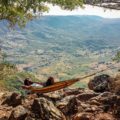 Tiago deitado na rede na beira de um precipício com uma vista para um vale e o mar ao fundo no Malawi