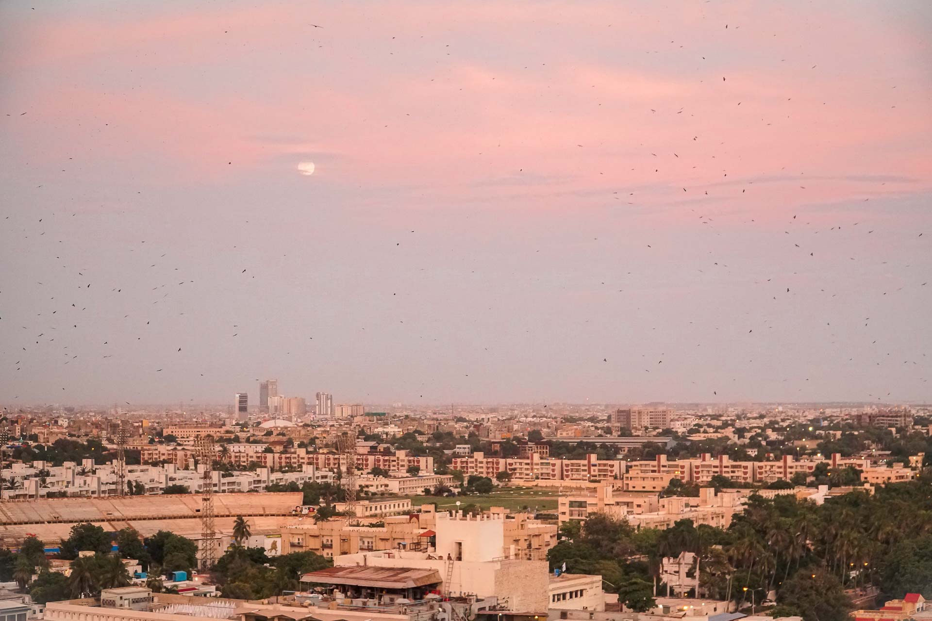 Um céu rosado com um sol no meio na cidade de Karachi no Paquistão