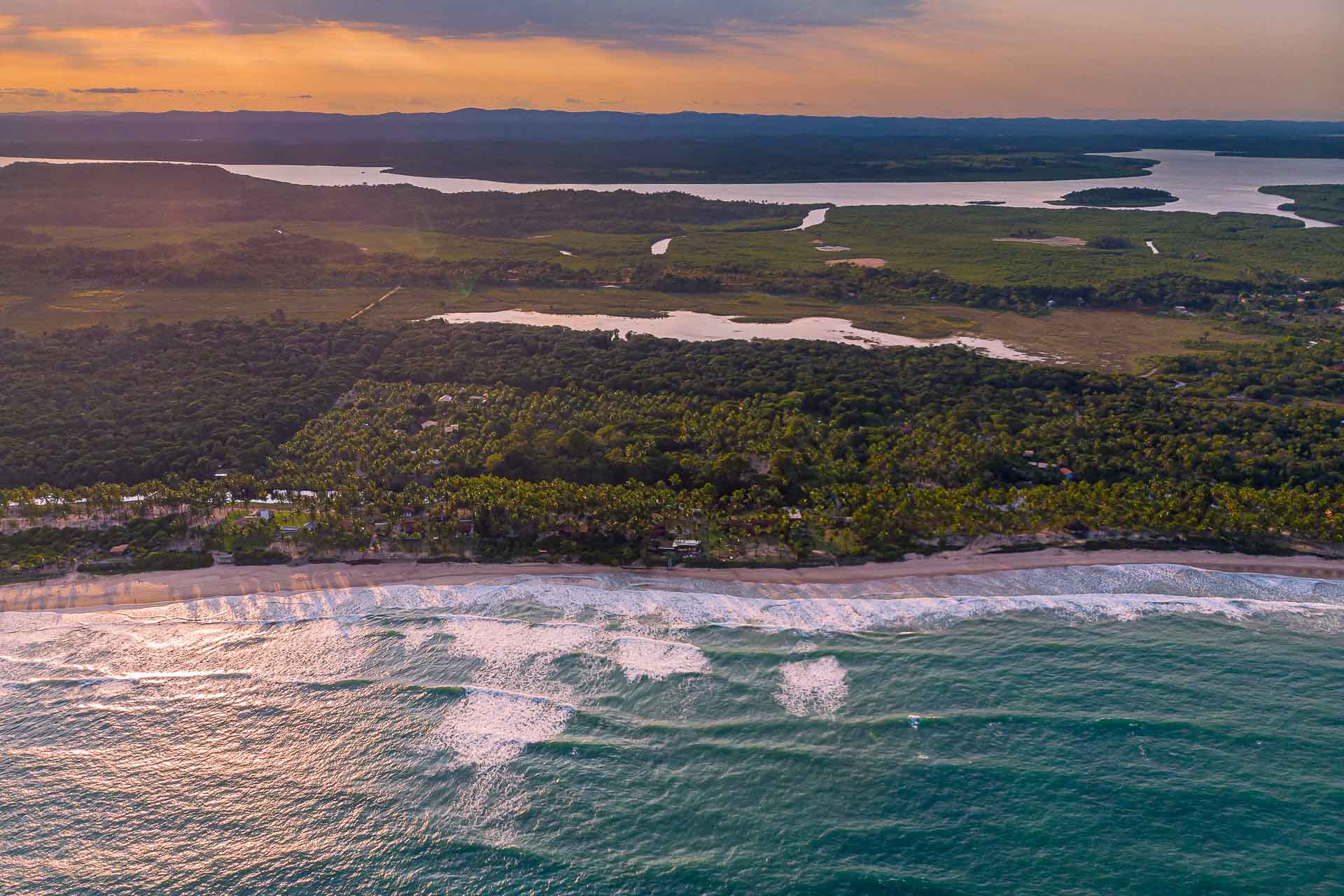 The beach from above with the sun setting behind clouds