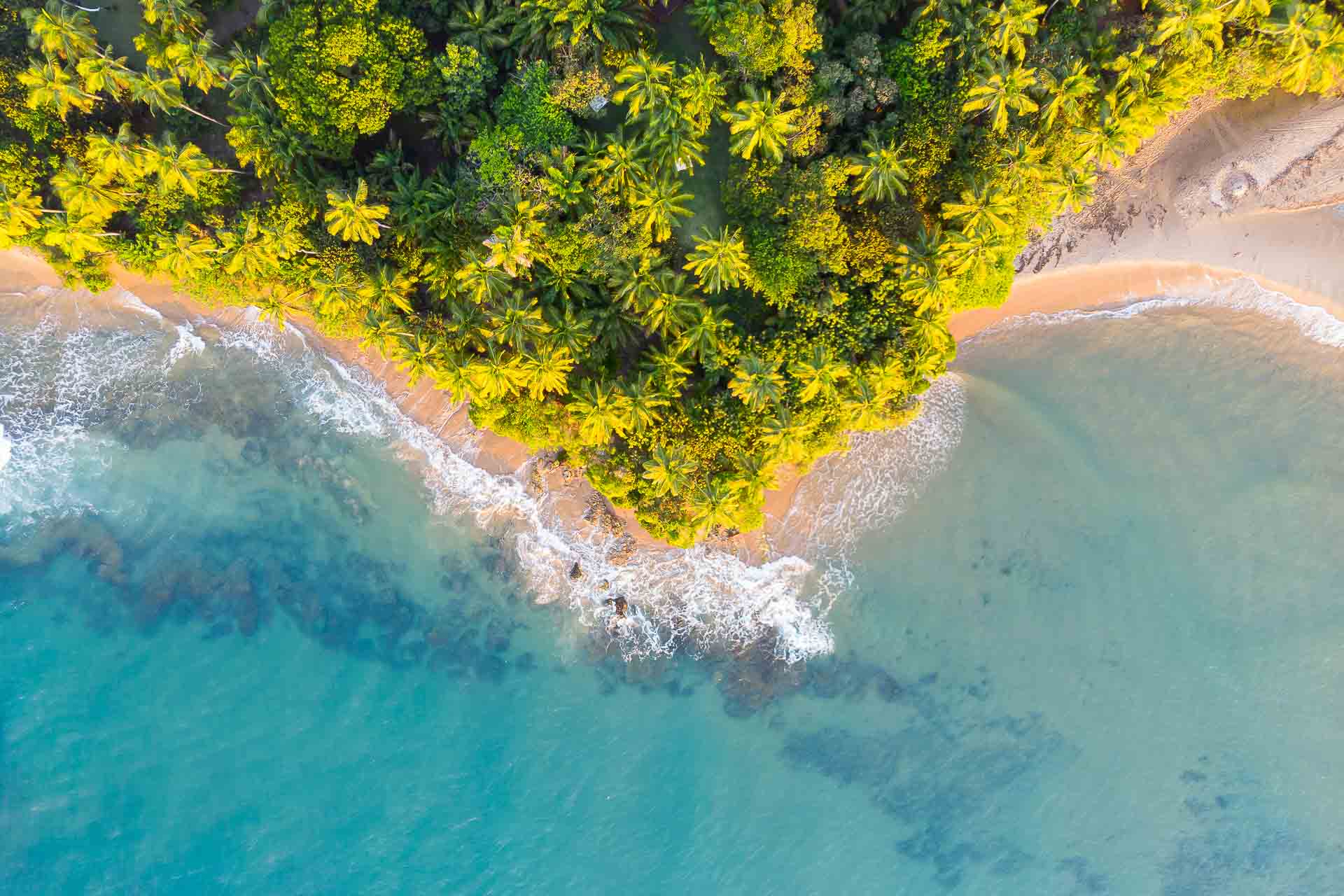 Aerial view of the Ponta do Muta 90 degrees with the waves hitting the rocks and many trees