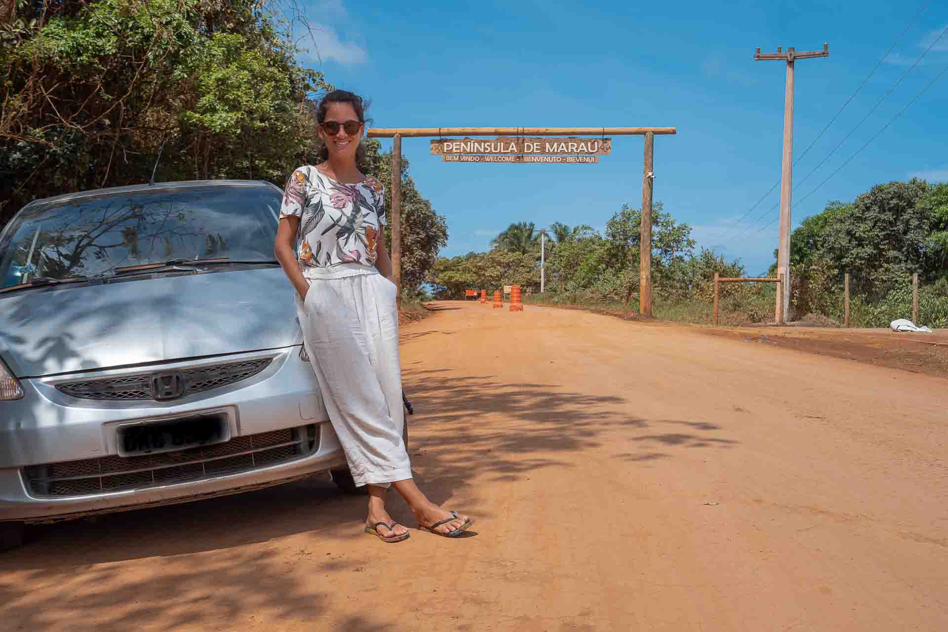 Fernanda ao lado do carro na estrada de terra da entrada da península de maraú