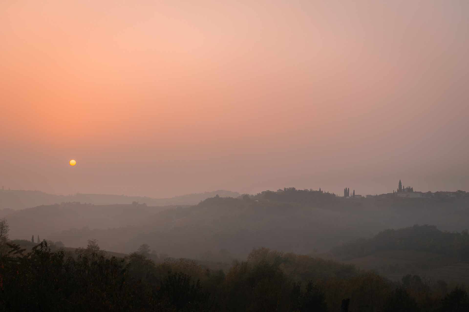 The sun setting in the horizon in a pinkish sky in Slovenia