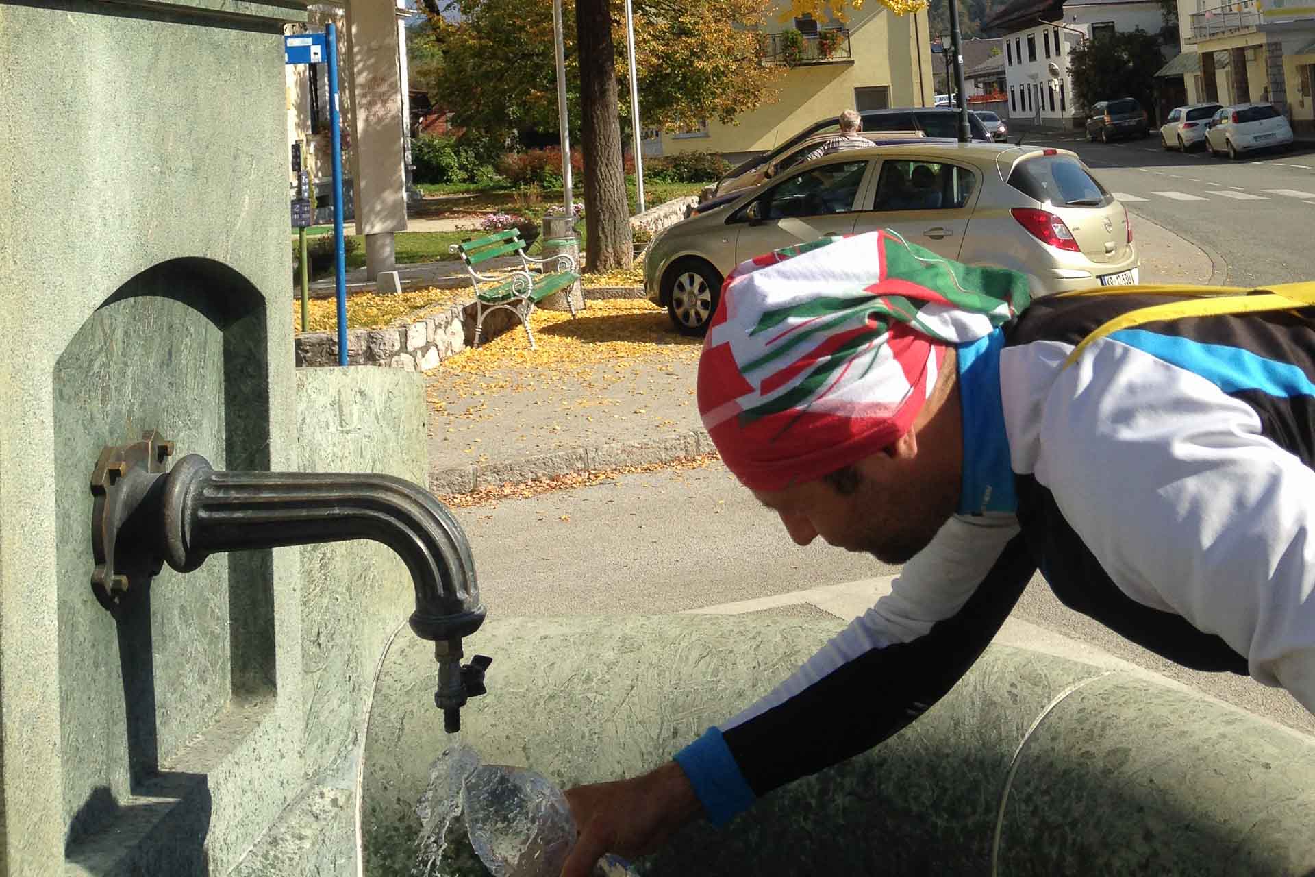 Tiago enchendo sua garrafa de água em uma bica dentro da cidade na Eslovênia