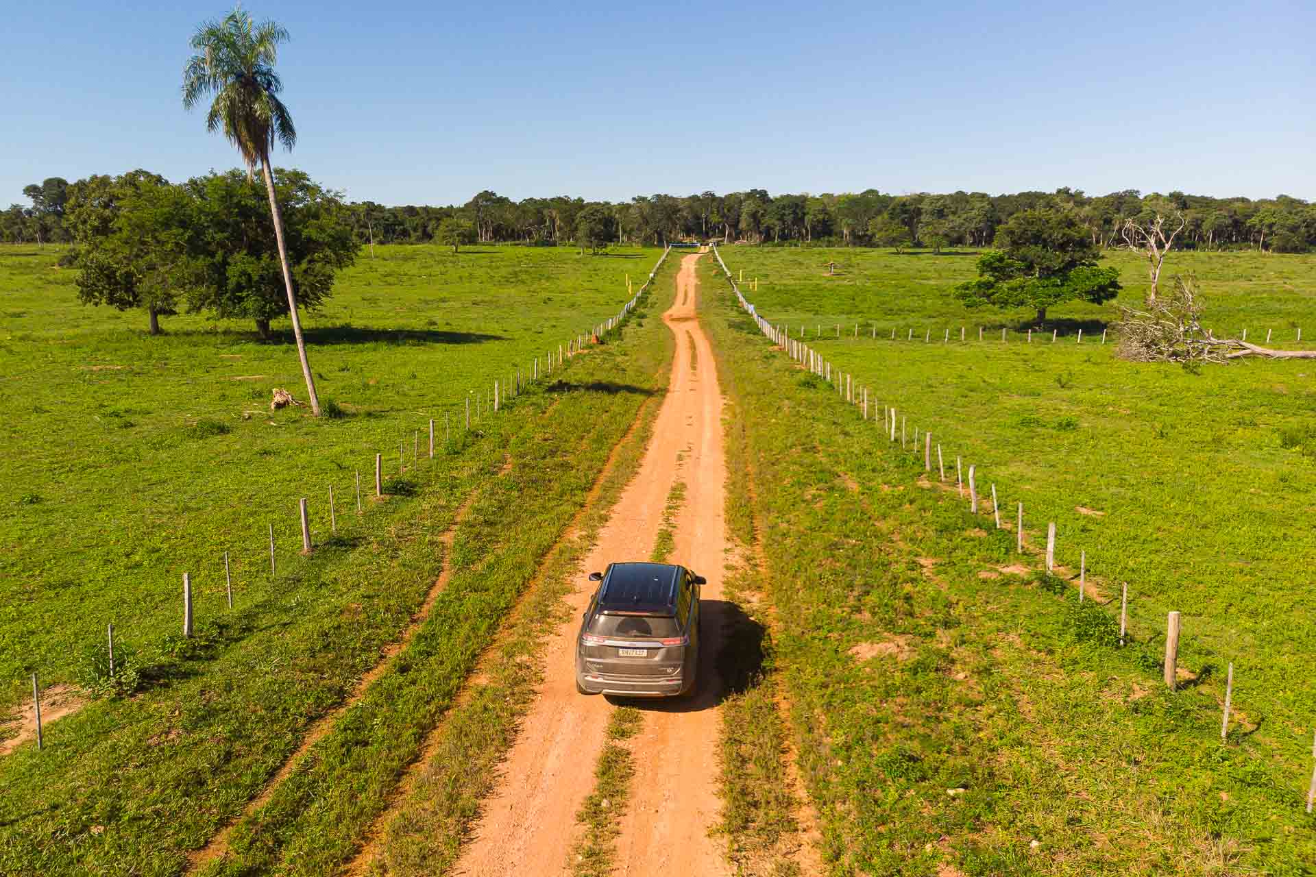 A car on a dirty road surrounded by a plain ground on a open sky
