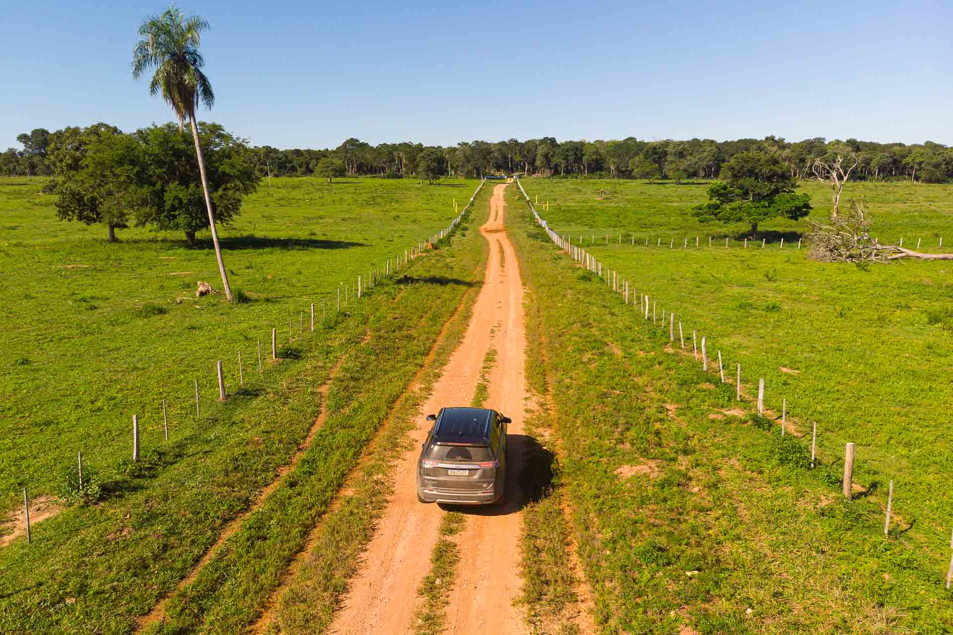 Carro jeep em estrada de terra batida em meio ao campo sem nada em volta