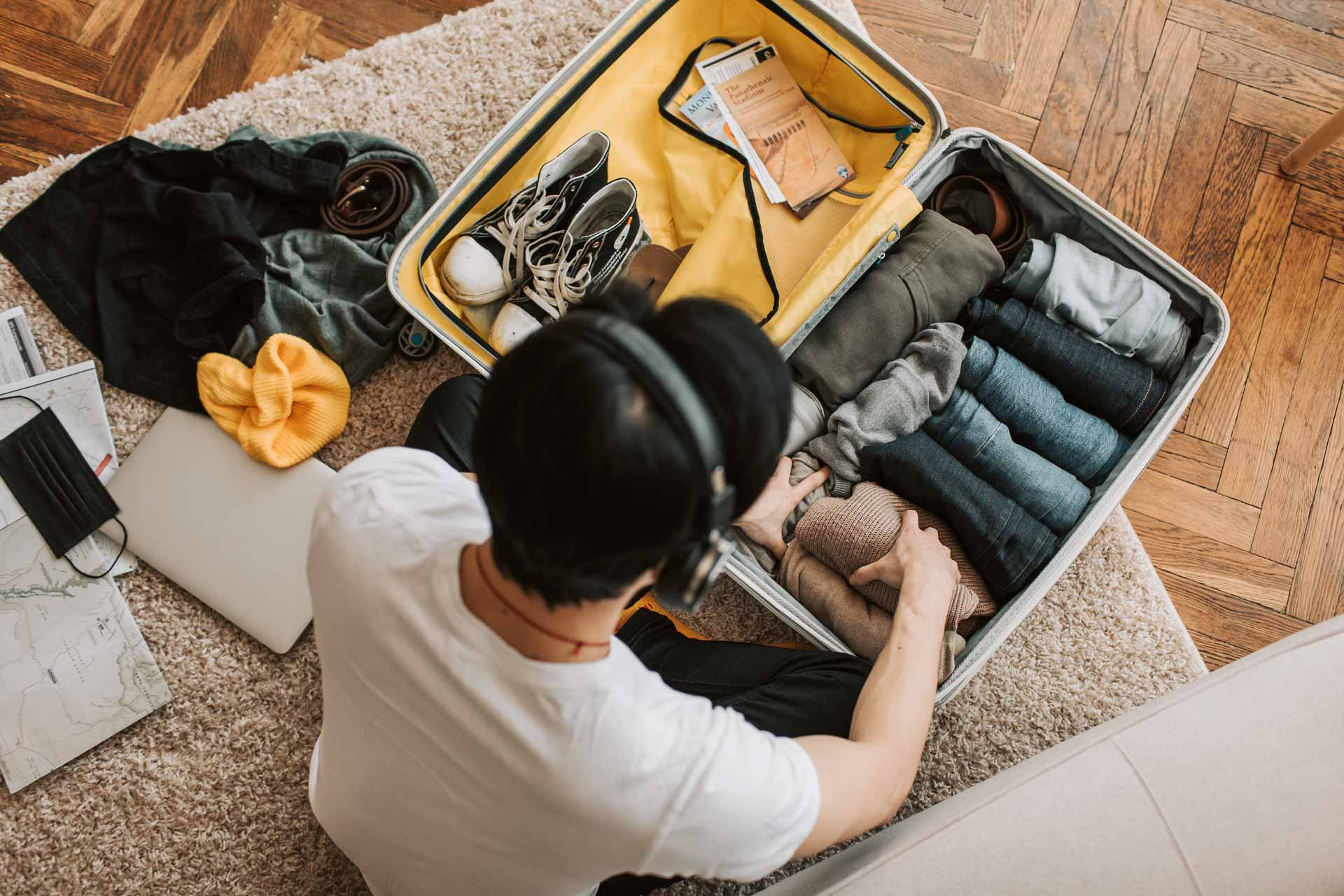 Man packing his bag to travel to fit everything he needs in a bag