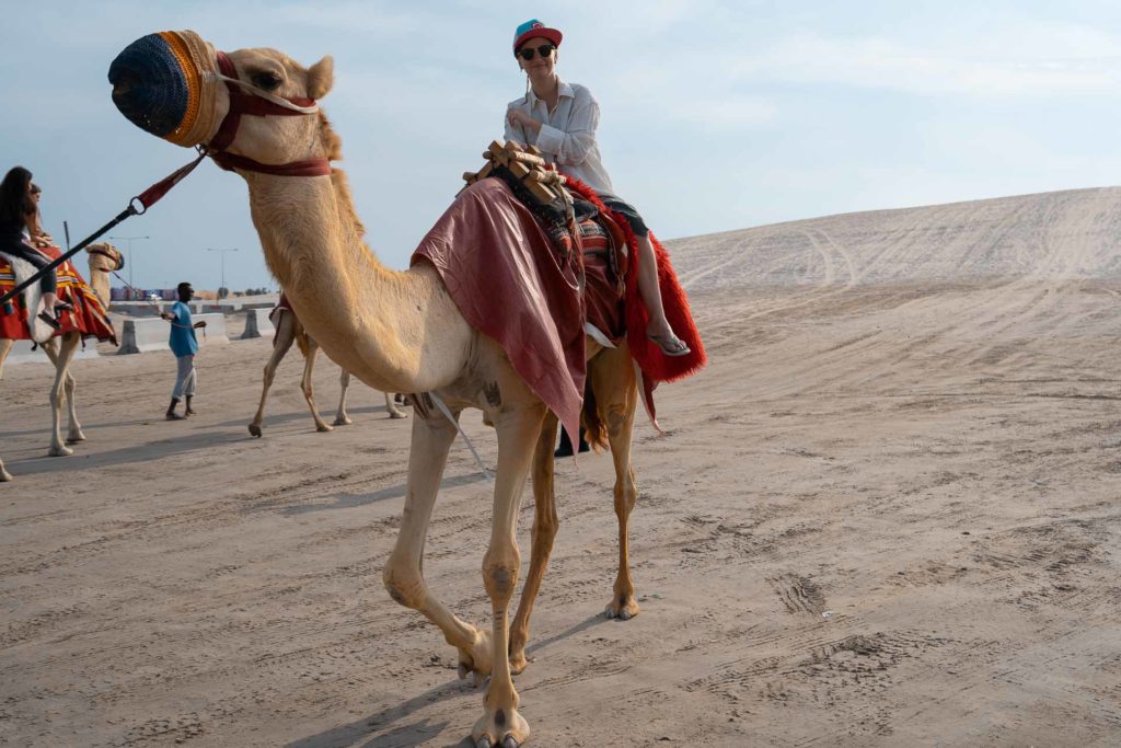 Um turista passeando de camelo durante o passeio no deserto do Catar
