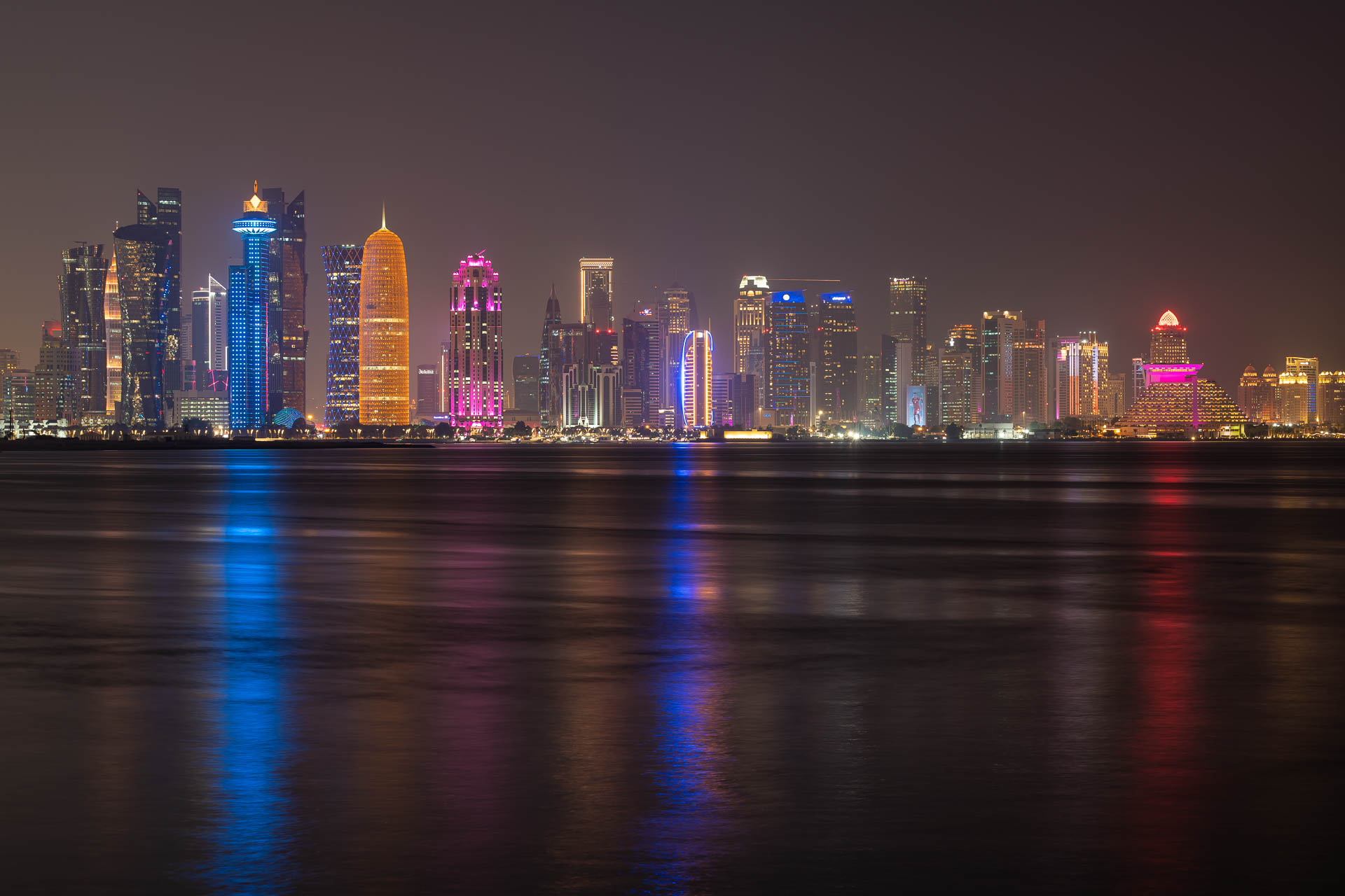 An overview of the city and large buildings of Central Doha at night