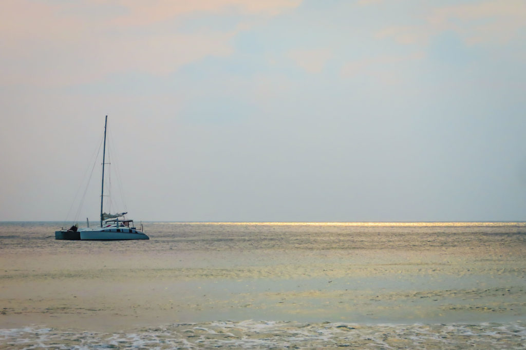 Barco navegando em alto mar com raios de sol no horizonte na água