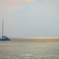 Barco navegando em alto mar com raios de sol no horizonte na água